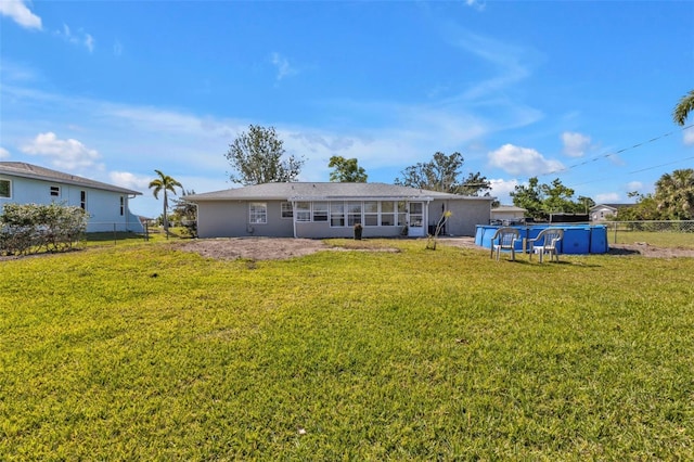 rear view of house with a lawn, an outdoor pool, and fence