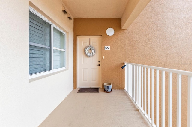 view of exterior entry featuring a balcony and stucco siding