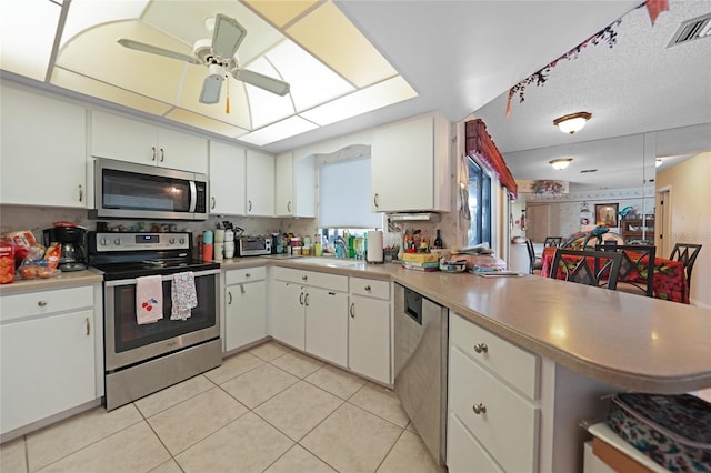 kitchen with light tile patterned floors, a peninsula, visible vents, light countertops, and appliances with stainless steel finishes