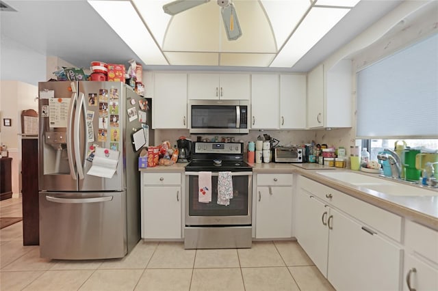 kitchen featuring ceiling fan, stainless steel appliances, a sink, and light countertops