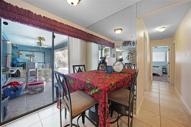 tiled dining area featuring a textured ceiling, ceiling fan, and baseboards