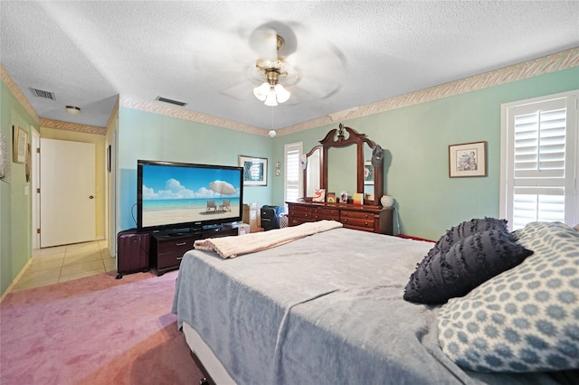 bedroom featuring light carpet, a textured ceiling, visible vents, and a ceiling fan