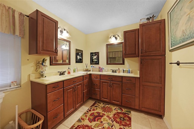 full bathroom with double vanity, a sink, a textured ceiling, tile patterned flooring, and baseboards