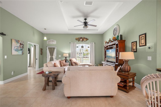 living area featuring visible vents, a raised ceiling, baseboards, and a ceiling fan