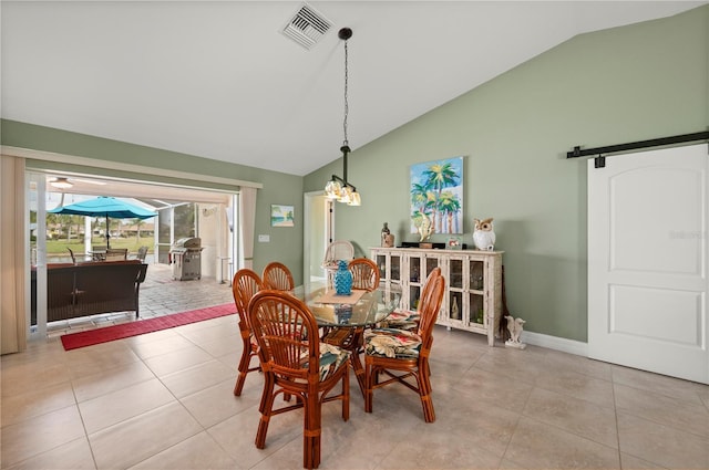 dining space with tile patterned floors, visible vents, a barn door, and vaulted ceiling