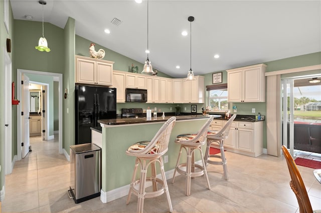 kitchen with black appliances, cream cabinetry, dark countertops, and a center island