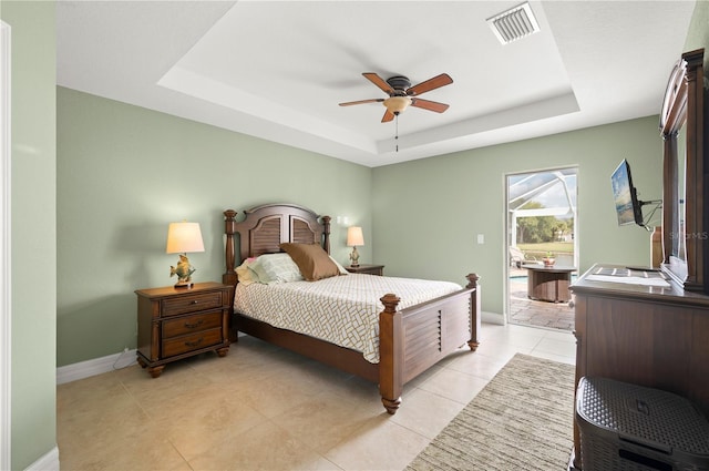 bedroom with baseboards, visible vents, a tray ceiling, light tile patterned flooring, and ceiling fan