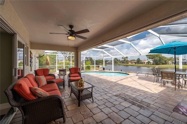 outdoor pool with glass enclosure, a ceiling fan, an outdoor living space, a water view, and a patio area