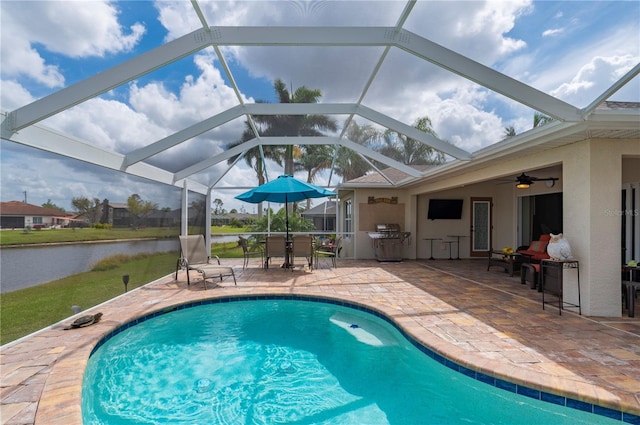 outdoor pool with a water view, glass enclosure, a grill, outdoor dining area, and a patio area