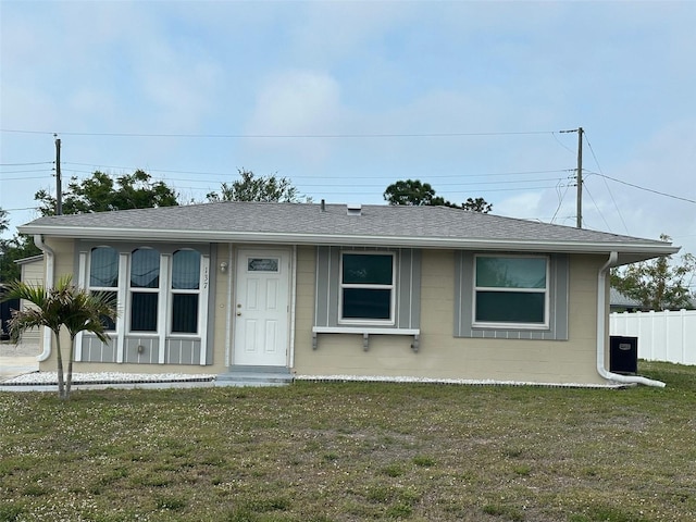 view of front of property featuring fence, a front lawn, and roof with shingles