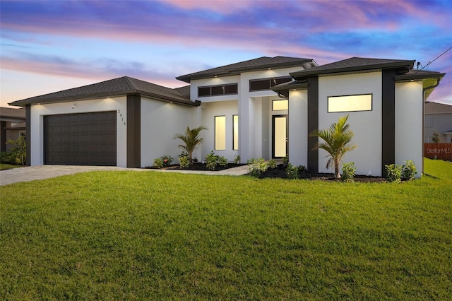 prairie-style house featuring driveway, an attached garage, a lawn, and stucco siding