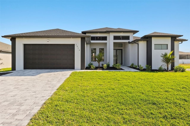 prairie-style house with an attached garage, a front yard, decorative driveway, and stucco siding