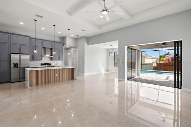 kitchen featuring visible vents, a ceiling fan, open floor plan, appliances with stainless steel finishes, and wall chimney range hood