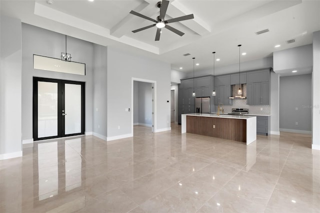 kitchen with visible vents, wall chimney exhaust hood, appliances with stainless steel finishes, open floor plan, and french doors