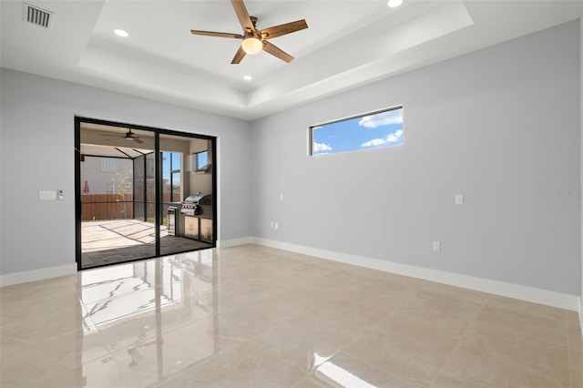 empty room with recessed lighting, a raised ceiling, visible vents, and baseboards