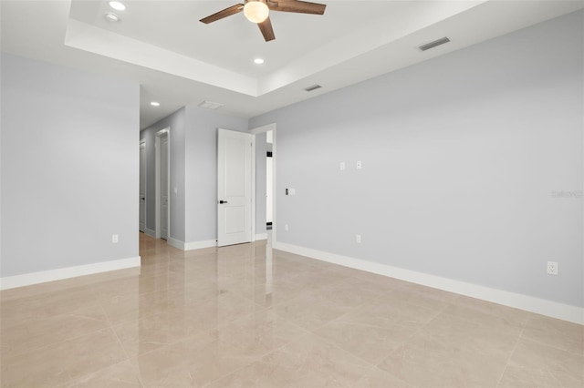 spare room featuring recessed lighting, a raised ceiling, visible vents, and baseboards