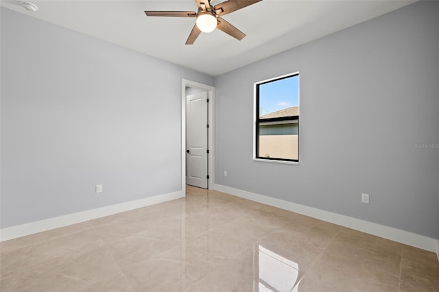 spare room with ceiling fan and baseboards