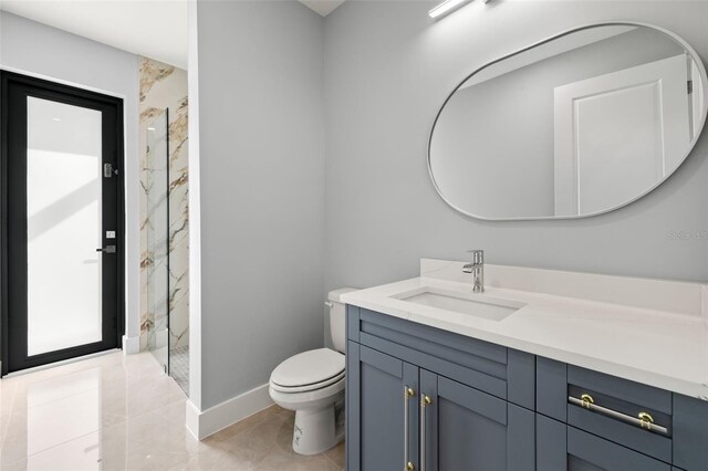 bathroom with toilet, a marble finish shower, baseboards, and vanity