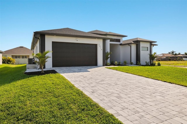 prairie-style house with a front lawn, decorative driveway, an attached garage, and stucco siding