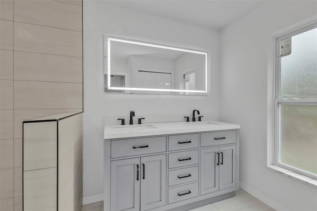 bathroom featuring double vanity, baseboards, and a sink