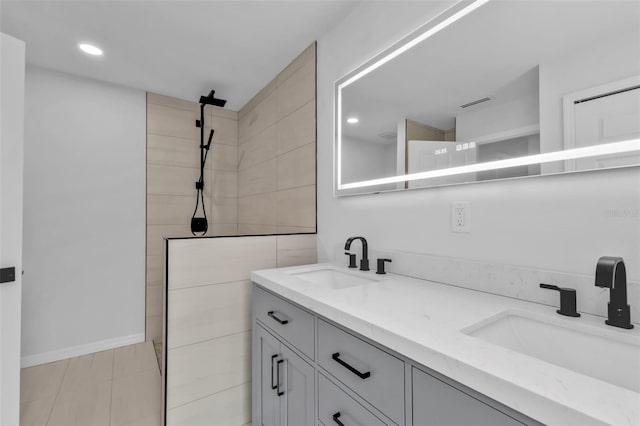 full bathroom with double vanity, a walk in shower, and a sink