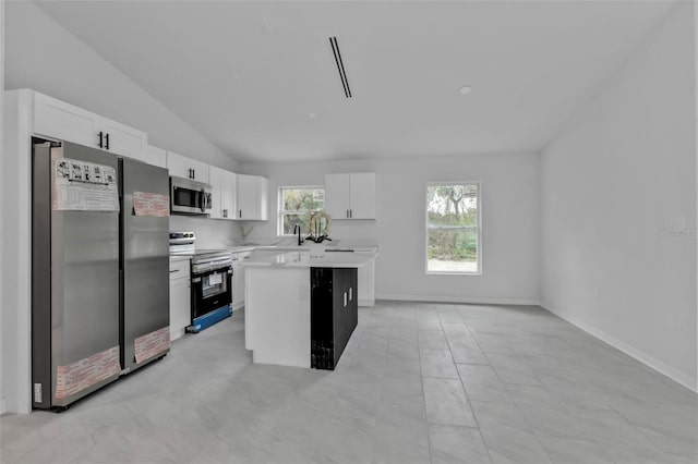 kitchen with white cabinetry, light countertops, appliances with stainless steel finishes, and vaulted ceiling