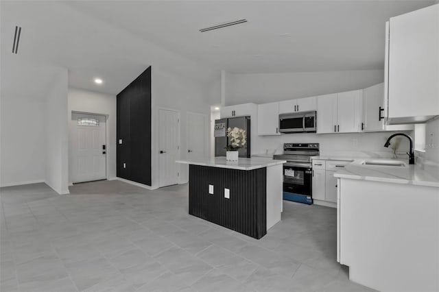 kitchen with a kitchen island, a sink, stainless steel appliances, light countertops, and white cabinets