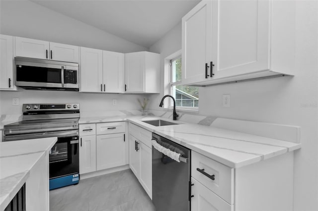 kitchen with a sink, light stone counters, stainless steel appliances, white cabinets, and lofted ceiling