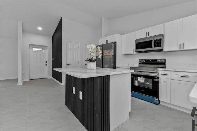 kitchen with light stone counters, white cabinets, appliances with stainless steel finishes, and a center island