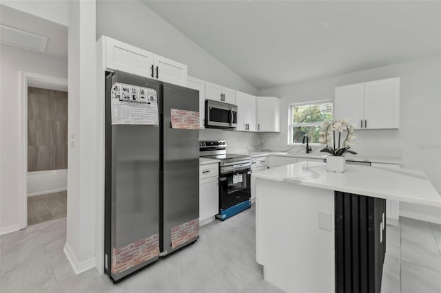 kitchen featuring a center island, stainless steel appliances, white cabinets, light countertops, and lofted ceiling