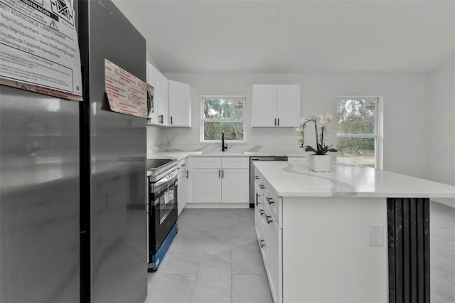 kitchen featuring a sink, stainless steel appliances, light countertops, white cabinets, and a center island