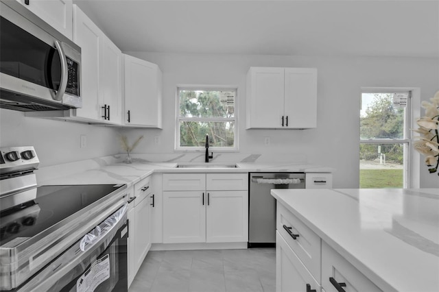 kitchen with a healthy amount of sunlight, white cabinets, stainless steel appliances, and a sink