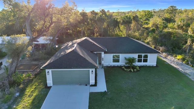 view of front of house featuring a front lawn, concrete driveway, stucco siding, a view of trees, and a garage