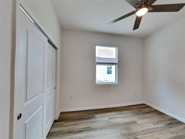 unfurnished bedroom with a ceiling fan, a closet, baseboards, and wood finished floors