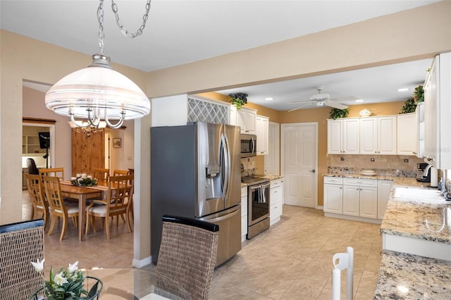 kitchen featuring light stone counters, a sink, stainless steel appliances, white cabinets, and backsplash