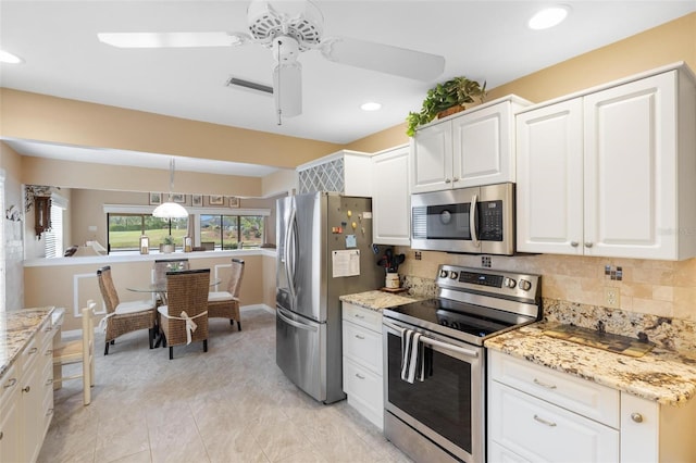 kitchen featuring pendant lighting, backsplash, appliances with stainless steel finishes, and white cabinets