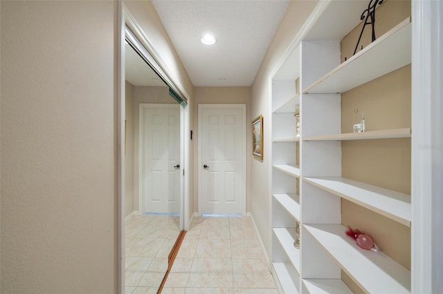 corridor with light tile patterned floors and baseboards