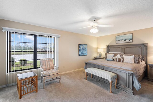 bedroom featuring ceiling fan, baseboards, a water view, light colored carpet, and a textured ceiling