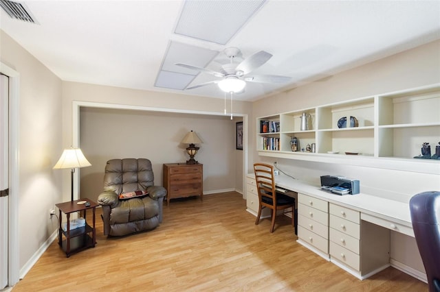 office space featuring a ceiling fan, visible vents, baseboards, light wood-style flooring, and built in desk