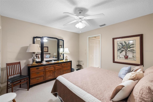 bedroom with light carpet, visible vents, a textured ceiling, and a ceiling fan