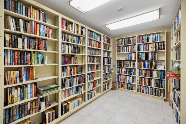 interior space featuring tile patterned floors and wall of books