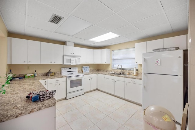 kitchen featuring visible vents, white appliances, white cabinetry, and a sink