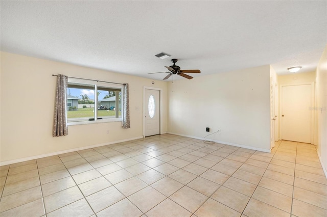 empty room with ceiling fan, light tile patterned floors, visible vents, and baseboards