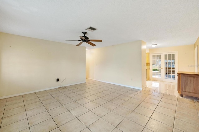 empty room featuring ceiling fan, light tile patterned floors, a textured ceiling, visible vents, and baseboards