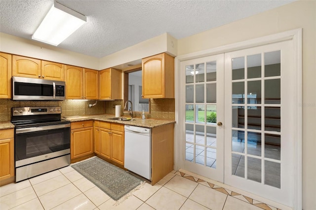 kitchen with stainless steel appliances, french doors, backsplash, and a sink