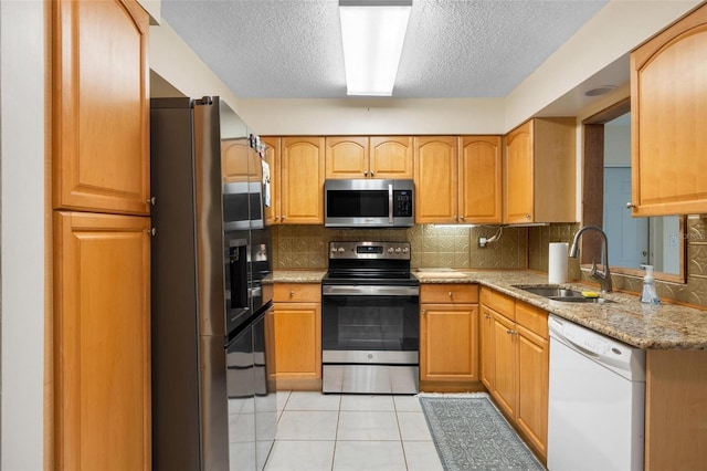 kitchen with light tile patterned floors, decorative backsplash, stainless steel appliances, and a sink