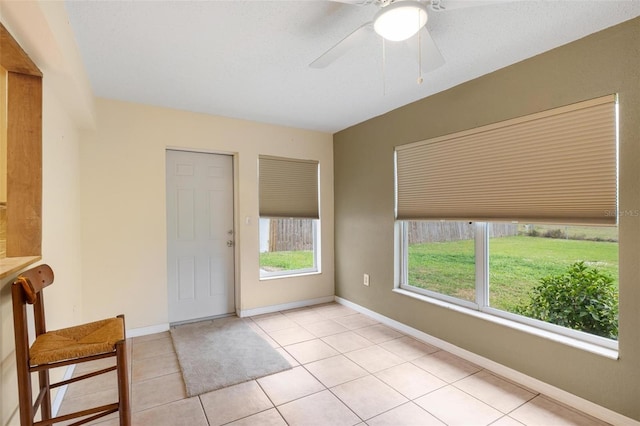 interior space featuring light tile patterned floors, baseboards, and a ceiling fan