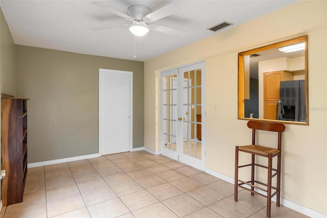 unfurnished room with light tile patterned floors, baseboards, visible vents, a ceiling fan, and french doors