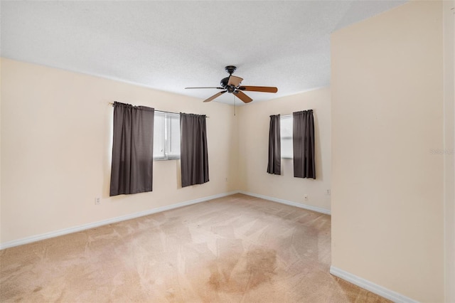 spare room with a healthy amount of sunlight, baseboards, a textured ceiling, and light colored carpet