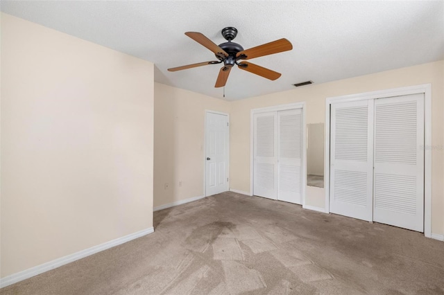 unfurnished bedroom with baseboards, carpet floors, visible vents, and multiple closets